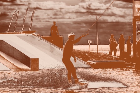 man riding by wakeboard in the pool. orange filter concept. extreme sport.