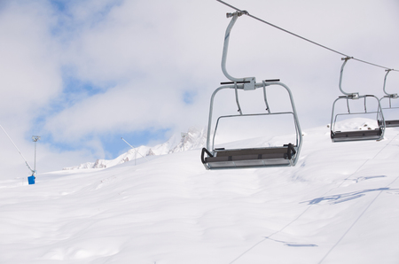 empty free chair ski lift on the snowboard resort with shadows on white snow background. Copy space for advertising.の写真素材