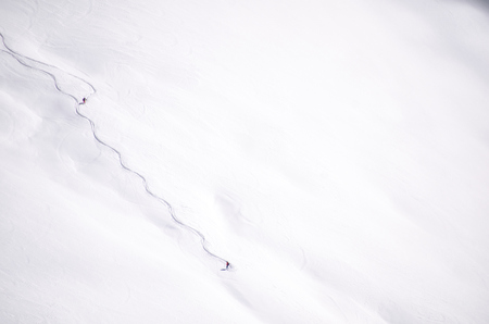 Freeride off-piste snowboard track in fresh white snow and freerider snowboarder moving down in snow...