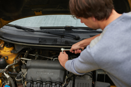 man turns nut wrench open the car hoodの写真素材