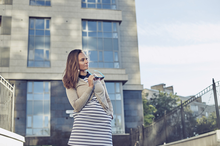 Beautiful woman walking in the big city. Thinking girl in the street with grey building background. Sport active person go home after training.の写真素材