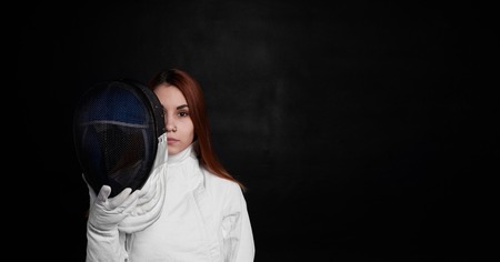 Red hair girl with fencing mask. Thinking emotion. Copy space for advertising text or goods.の写真素材