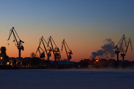 Industrial sea port in winter time. Crane on mornin sky background. Work city landscape.の写真素材