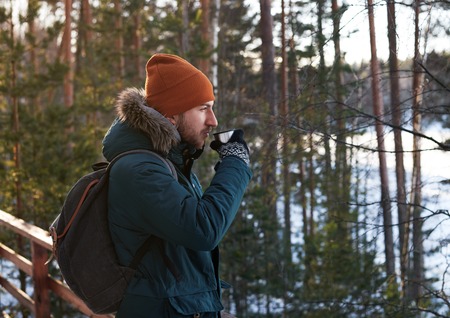 Portrait of handsome bearded man drinking hot tea outdoor in forest trip on foot. Strong and brave...