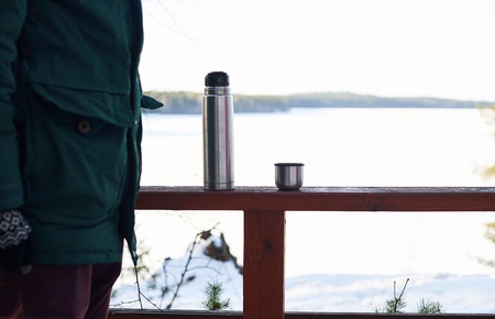 Part of tourist in forest trip. Relax and rest time with pot of hot tea with winter snowy landskape background. Copy space for advertising travel goods or tourism stuff.の写真素材