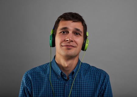 Happy man listen good music. Relaxing concept of european man with headphones in studio with grey background. Face with joy emotion.の写真素材