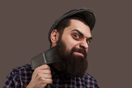 Spiteful brutal bearded man shave by axe. Portrait of hipster with beard. Hot-tempered male concept. Crazy emotion on face.の写真素材