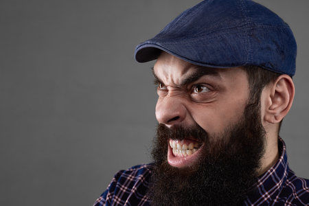 Aggressive emotion with open mouth of bearded man on grey background. Repulsive face. Malignant guy. Free space for the text. Angry person. Close up portrait of fear.の写真素材