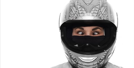 Close up portrait of crazy wowan with extereme life. Lady in motorcycle helmet on white background. Strabismus young girl. Funny female concept. Copy space for advertising motorbike goods.の写真素材