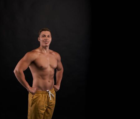 Happy smiling bodybuilder stay and look to the camera on dark background with naked body. Trained person shot. Health and sport life concept.の写真素材