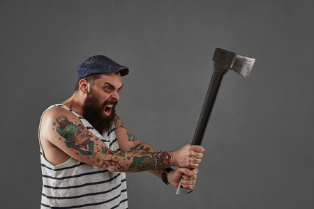 Aggressive tattoo big bearded man with ax. Shout person with open mouth. Businessman after hard work. Angry manager concept.の写真素材