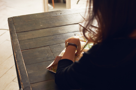 Back view on brunette woman writing notes with free space for advertising product on wooden table. Indoor loft concept.の写真素材