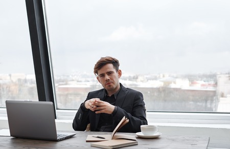 Bussiness man with stylish look in his office with window wall background sitting and look to the camera. Chief meet job seeker for interview.の写真素材