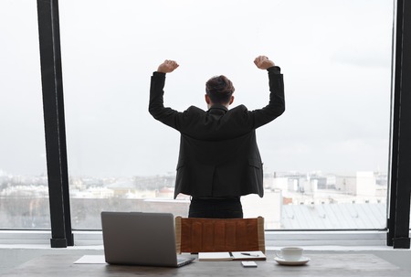 Mindful experienced sales manager of trading company have relax after hard work all the day in office. He finished startup during last month. Back view on the boss who look to the big window.の写真素材