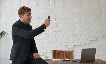 Aggressive Chief in office in black suite holding shouting at mobile phone. Dramaatic moment in bank dept of credit. Man receive worry mail about bad health of his relative.の写真素材