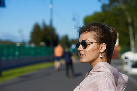 People and lifestyle concept. Profile of fashionable attractive student girl in round shades walking in park after college, enjoying warm sunny day, breathing fresh air, feeling free and relaxedの写真素材