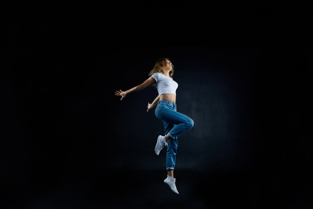 Studio shot of beautiful young European woman dancer with slim flexible body practising indoors, sharpening her dancing skills, dressed in sensible clothing. People, hobby and active lifestyle conceptの写真素材