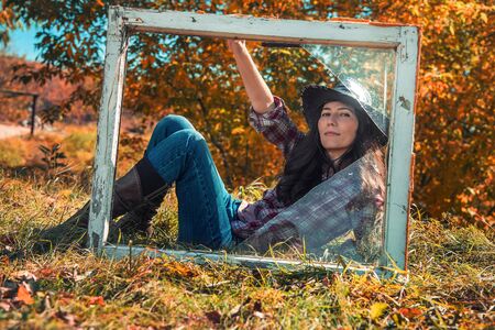 portrait of Young adult woman sit on windowsill in grassの写真素材
