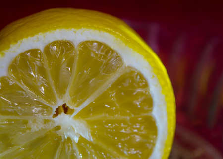 Fresh juicy sliced lemon on a glass plate and dark red backgroundの写真素材