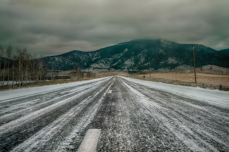 The winter road in a forest to mountainの写真素材