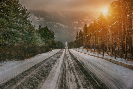 The winter road in a forest to mountainの写真素材