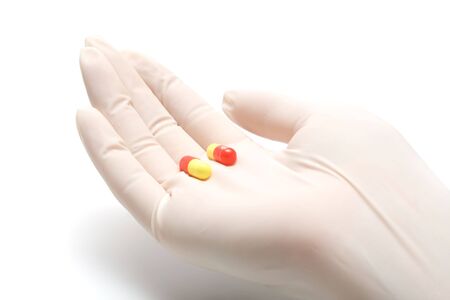 Helping hand in latex glove giving pills, isolated, on white background  の写真素材