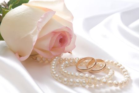 Rose, pearl necklace and  rings over white satinの写真素材