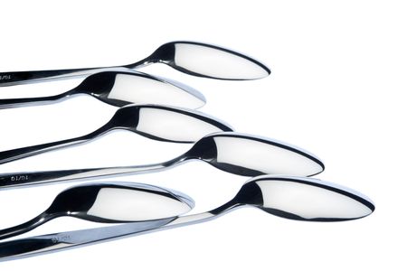 Six 18/10 steel table-spoons, lying upside down, isolated