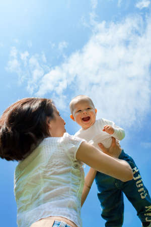 Mother throwing baby against blue sky