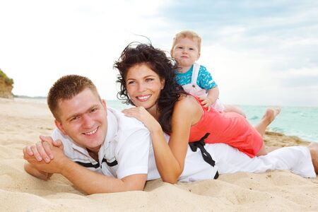 Laughing family lying on the sand in summerの写真素材