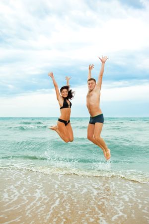 Happy young couple jumping in the seaの写真素材