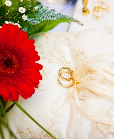 Two golden wedding rings lying on the pillowの写真素材