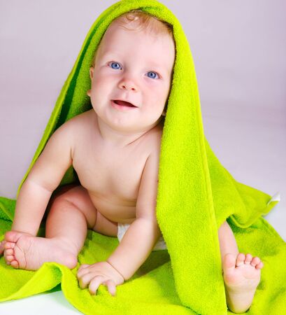 Cheery baby covered with a green bath towelの写真素材