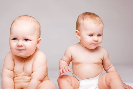 Two sweet babies in diapers, on a grey backgroundの写真素材