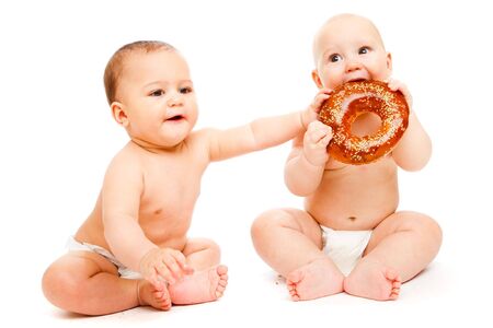 Two sweet babies in diapers eating breadの写真素材