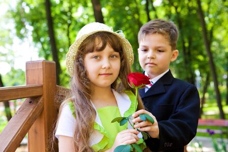 Preschool boy in suit giving a rose to the sweet girlの写真素材