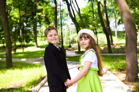 Preschool boy in suit and a sweet little lady holding handsの写真素材