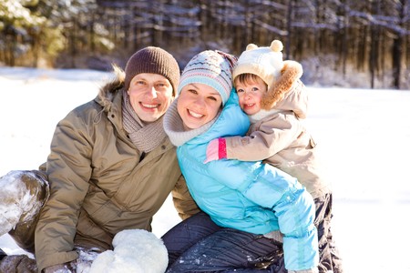Toddler girl and her parents in a snowy parkの写真素材