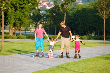 A happy family skating in a summer parkの写真素材