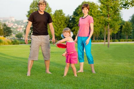 Preschool girl throwing plastic disc in parkの写真素材