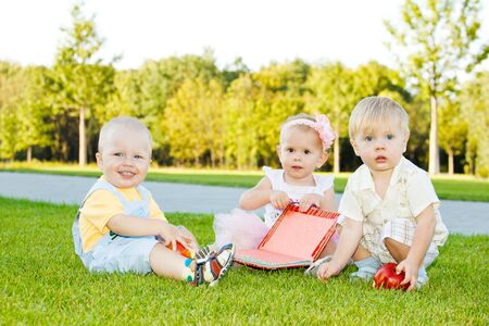Three toddlers sitting on grassの写真素材