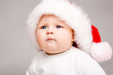 Portrait of a cute baby in a Santa hat, over grayの写真素材