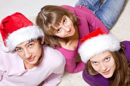Teenage friends in Santa hats looking up