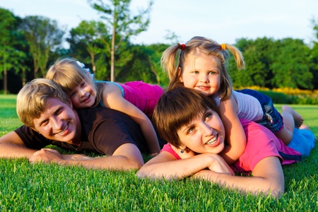 Parents with little daughters  on the green grassの写真素材