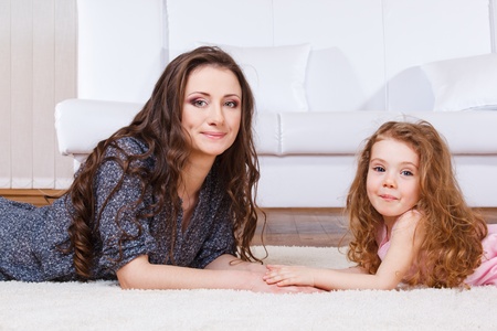 Pretty woman and sweet girl with long hair lying on the floor together. の写真素材