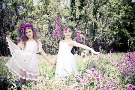 Two lovely girls with headwreaths, holding handsの写真素材