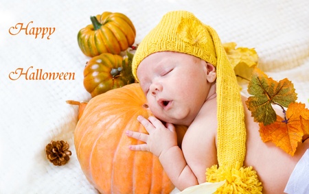 Happy halloween greeting card with baby sleeping on a pumpkinの写真素材