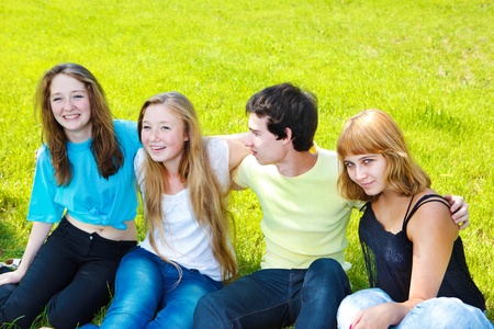 Teenage friends sit on grass, huggingの写真素材