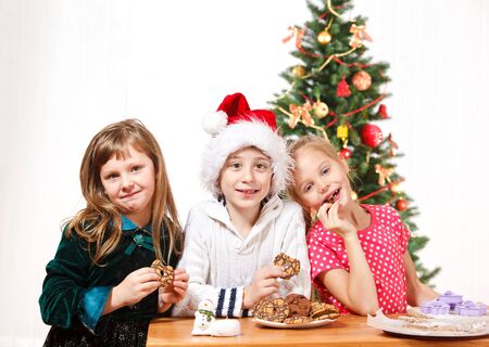 Three kids eating Christmas cookiesの写真素材