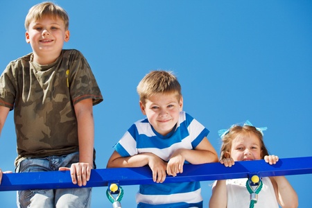 Three kids climbing up the playground net の写真素材